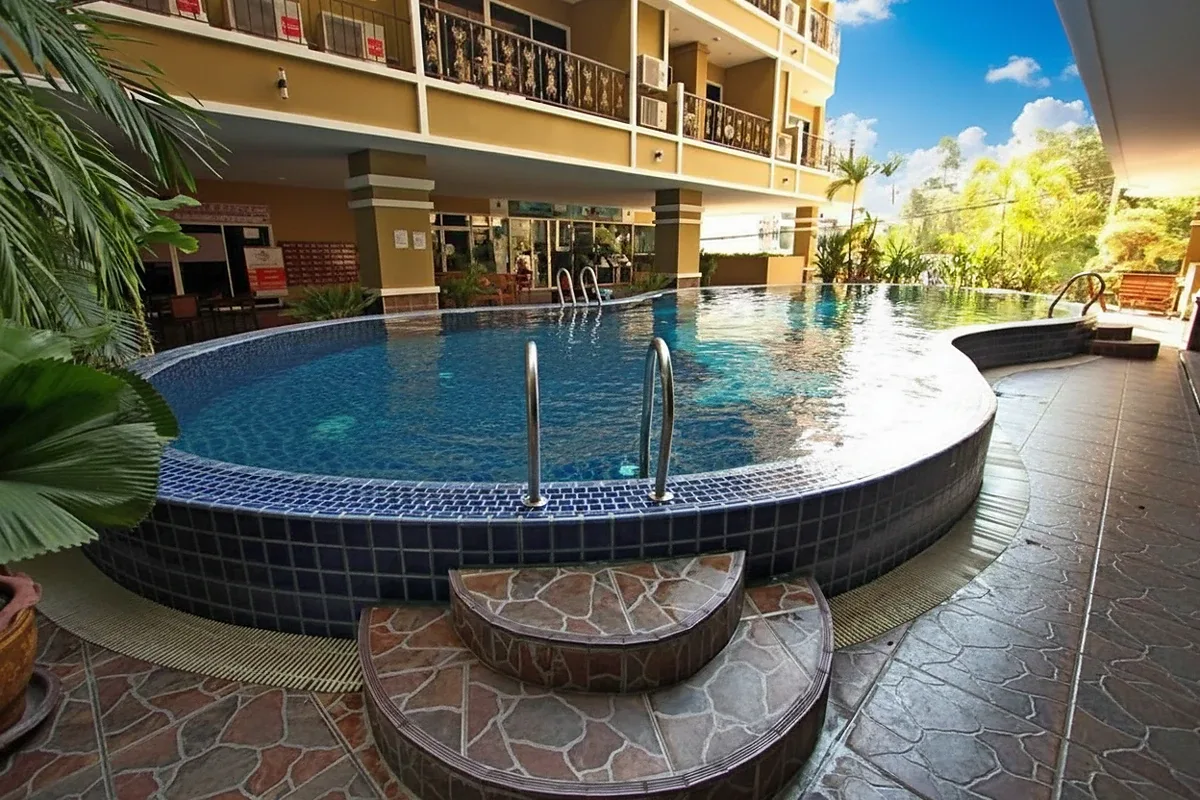 Siam Oriental Twins kidney-shaped swimming pool with blue tiles and steps, reflecting sunlight.
