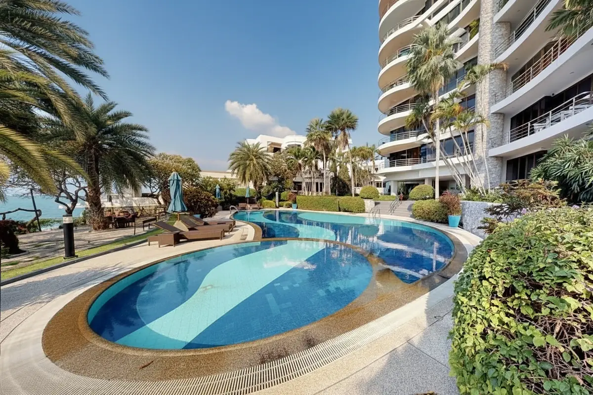 Sugar Beach resort pool with blue and white tiles, surrounded by palm trees and a modern building.