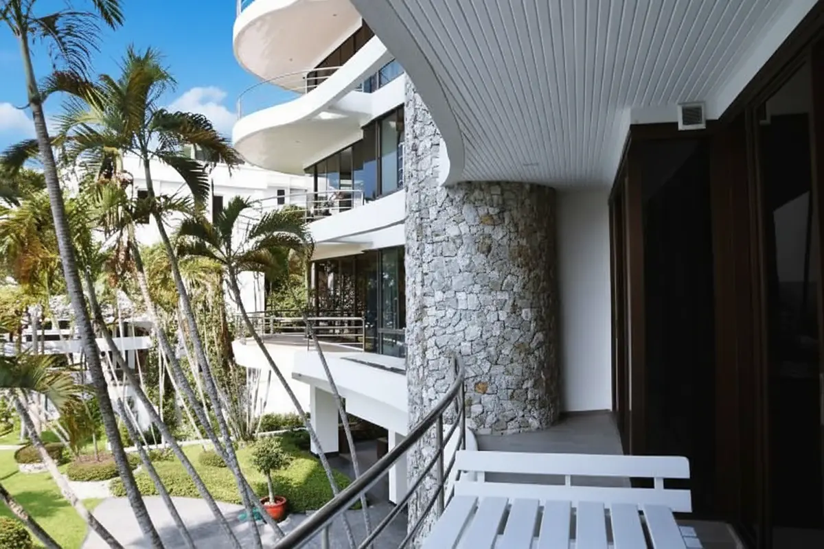 Sugar Beach condo exterior with curved balconies, stone facade, and lush palm trees.