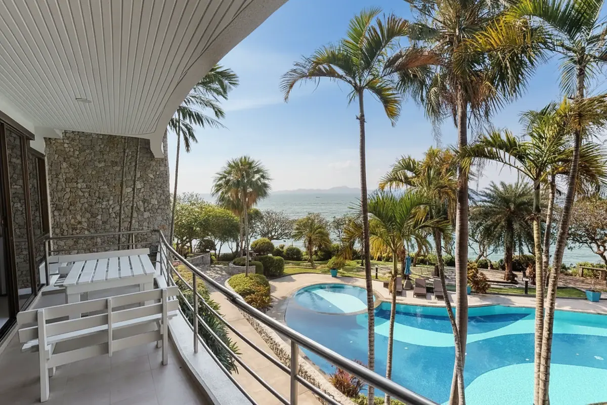Sugar Beach balcony with white bench, overlooking palm trees, pool, and ocean.