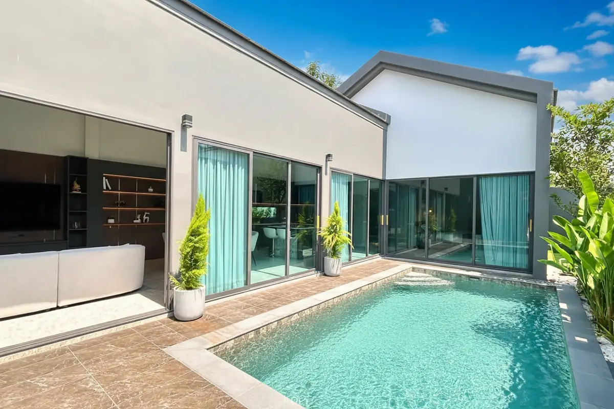 The Hamlet Pattaya, exterior view of a modern house with a private swimming pool, large sliding glass doors, and tropical plants.