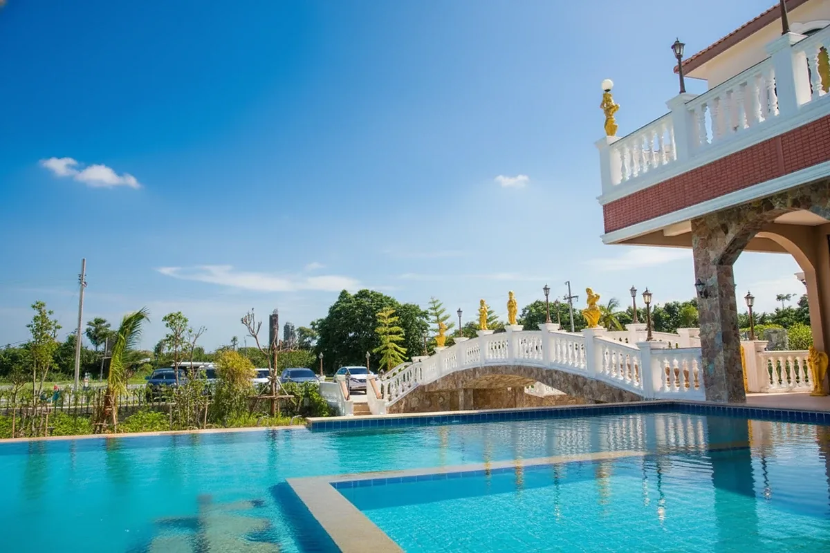 The Lake Huay Yai grand clubhouse building with a decorative bridge, golden statues, and a water feature.