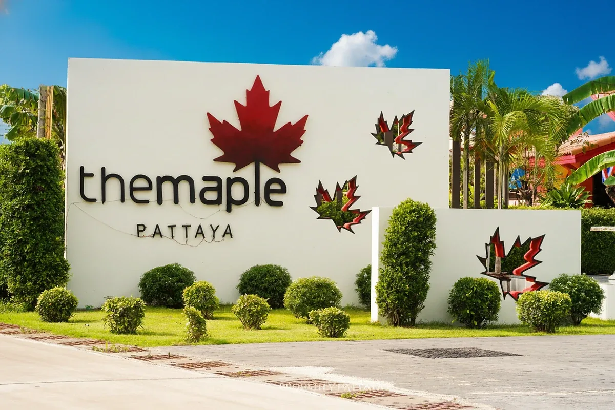 The Maple Pattaya entrance sign with a large red maple leaf logo and manicured shrubs.