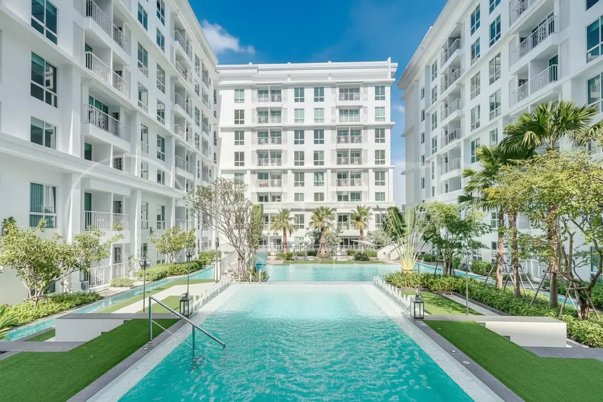 The Orient Resort & Spa exterior view of white condo buildings surrounding a long swimming pool and green courtyard.