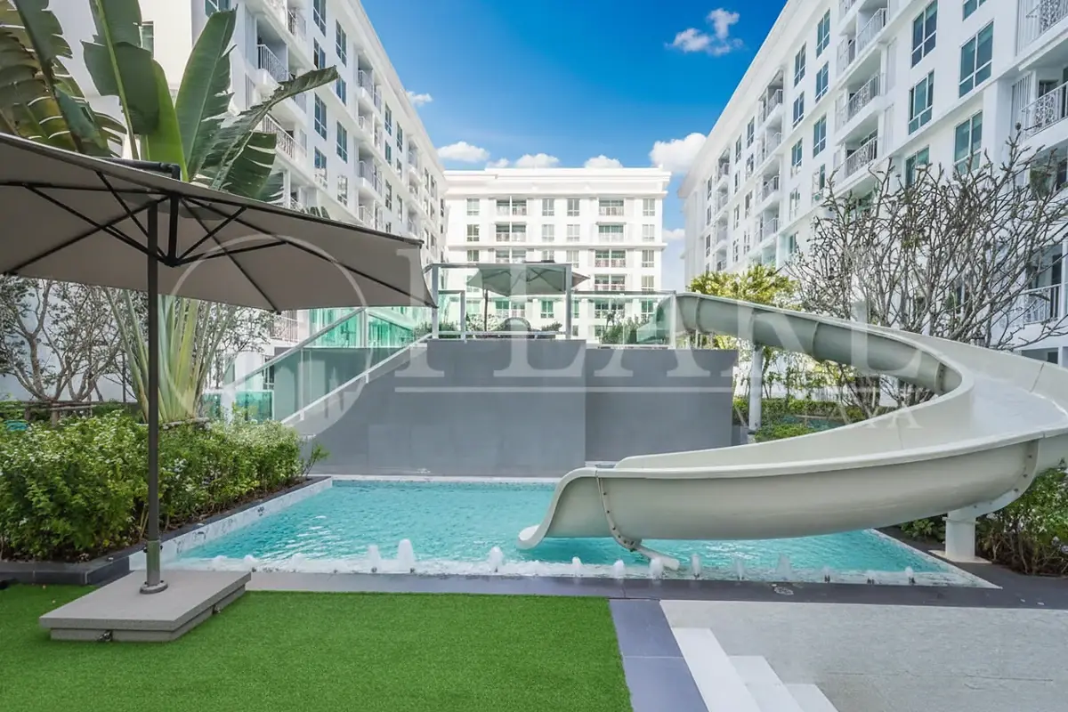 The Orient Resort & Spa outdoor swimming pool area with a water slide and surrounding lush greenery.