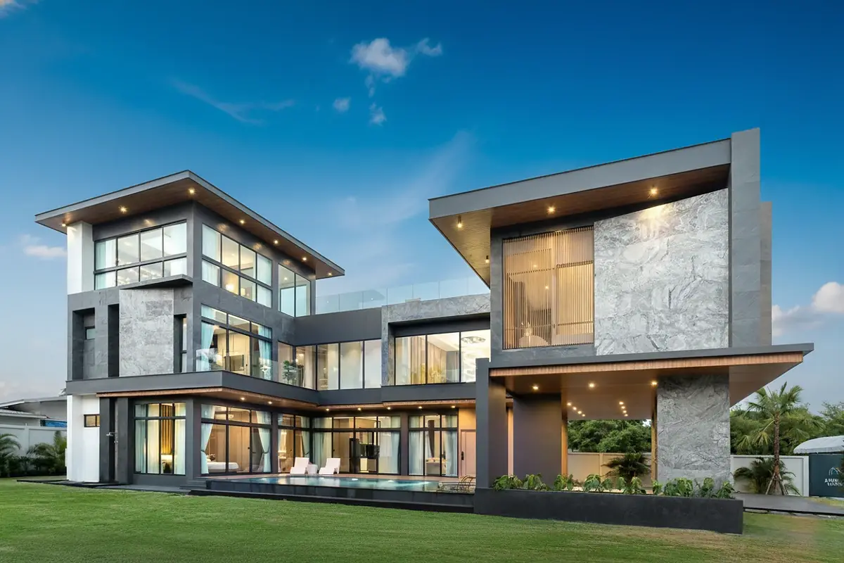 The Sylva Pattaya contemporary house exterior with pool, extensive glazing, and stone accents at dusk.
