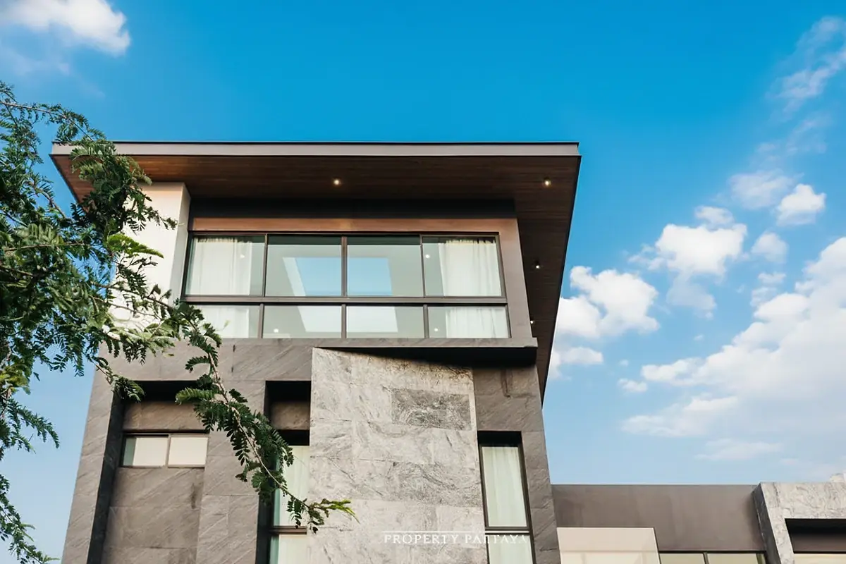 The Sylva Pattaya upper floor exterior with stone cladding, large windows, and a clear blue sky.