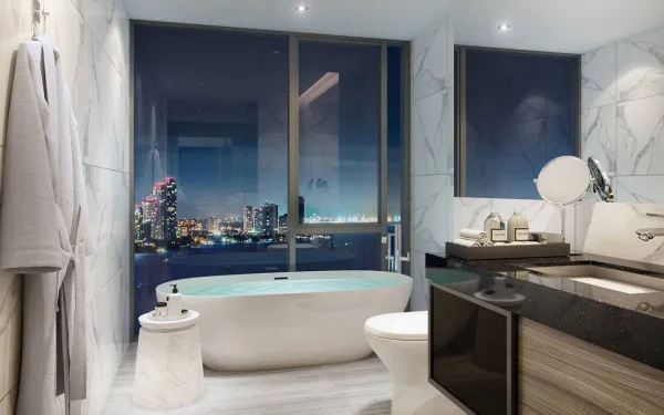 The Panora Pattaya open-plan kitchen and living area at night, with a dining table and ocean view.