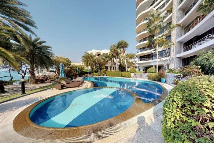 Sugar Beach resort pool with blue and white tiles, surrounded by palm trees and a modern building.
