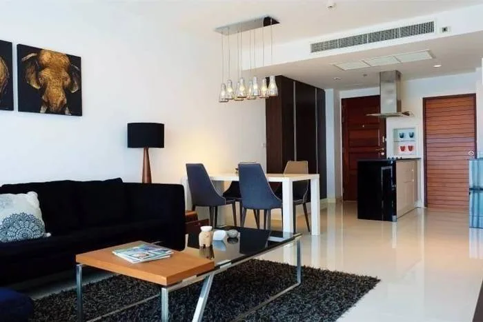 Axis Pattaya Condo street view of the modern condo building with cars parked along the road and lush trees.