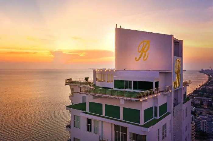 The Residences @ Dream Pattaya aerial view of the illuminated high-rise building and Pattaya coastline at dusk.