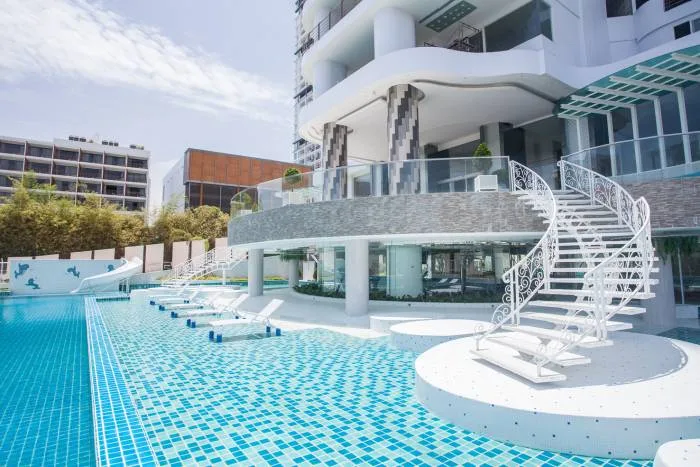 The Residences @ Dream Pattaya rooftop with a large 'R' logo, terraces, and ocean view at sunset.