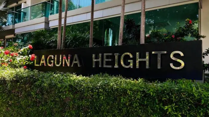 Laguna Heights building exterior with green glass facade, lush landscaping, and prominent signage.