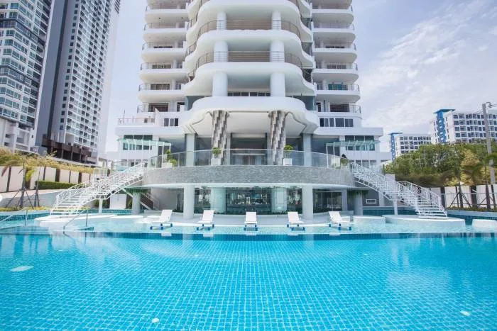 The Residences @ Dream Pattaya aerial view of the large outdoor swimming pool with a person swimming and lounge area.