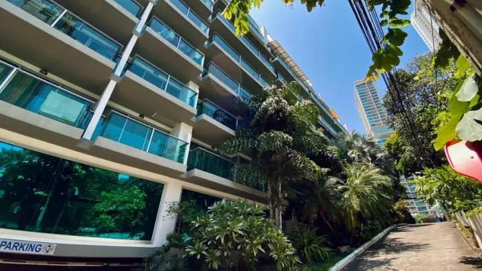 Laguna Heights modern building exterior with glass balconies, lush tropical plants, and parking entrance.