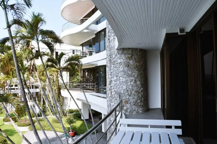 Sugar Beach condo exterior with curved balconies, stone facade, and lush palm trees.