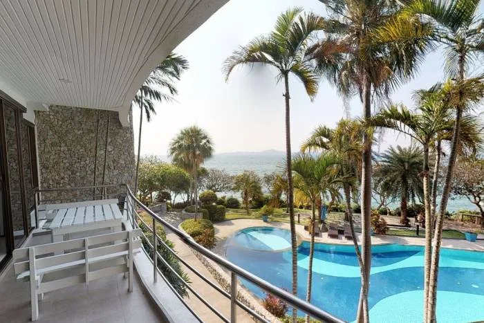 Sugar Beach balcony with white bench, overlooking palm trees, pool, and ocean.