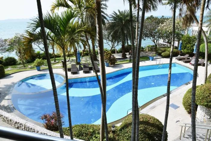 Sugar Beach resort pool with lounge chairs, surrounded by palm trees and ocean in the background.