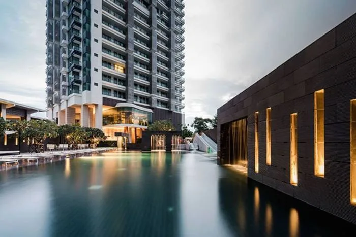 Reflection Jomtien Beach: Infinity pool overlooking the ocean with sun loungers and a bright sunset sky.