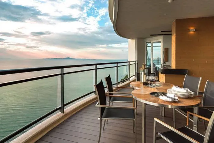 Reflection Jomtien Beach: Upward view of two tall, modern condo towers against a blue sky with white clouds.