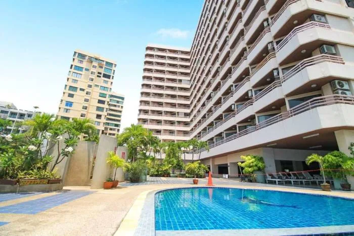 Kieng Talay tall condo building exterior with balconies, glass elevator, swimming pool, and Pattaya Tower in background.