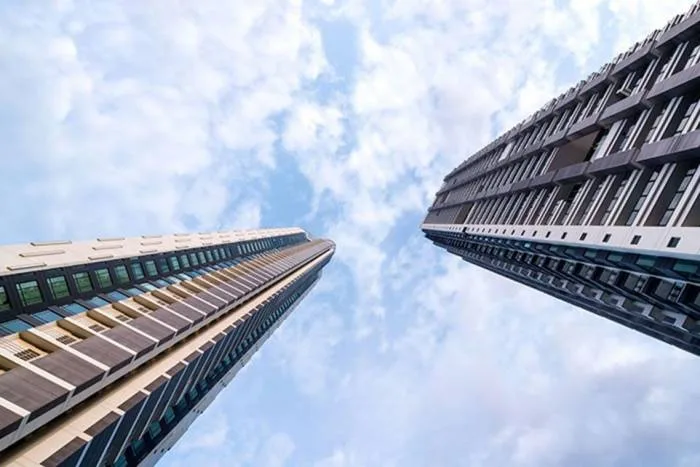 Reflection Jomtien Beach: Modern high-rise building and a dark textured building with illuminated waterfall features by a large pool.