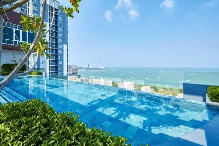 Centric Sea rooftop infinity pool at dusk with city lights and ocean view.