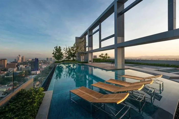 Centric Sea rooftop infinity pool at dusk with city lights and ocean view.