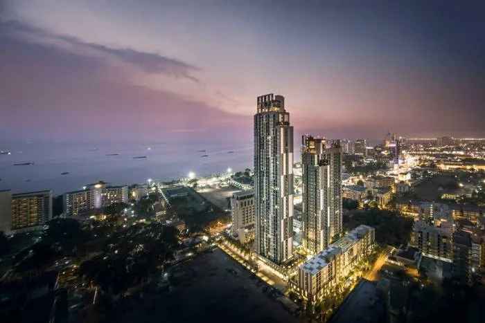 Centric Sea aerial view of two illuminated condo towers at dusk overlooking Pattaya city and ocean.