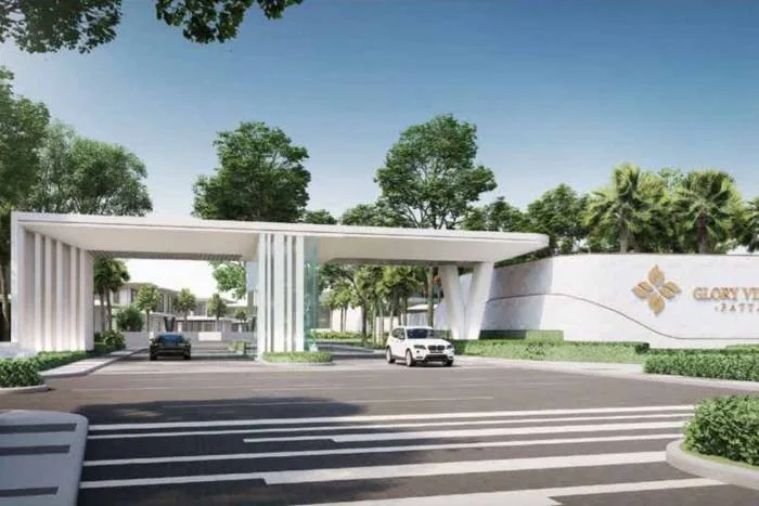 Glory Village Pattaya main entrance gate with modern design, white walls, and lush greenery.