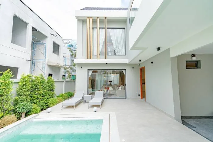 The Infini Pattaya modern house exterior with a small swimming pool, two lounge chairs, and a sliding glass door to the living room.