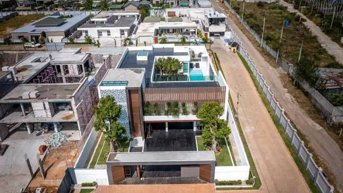The Prestige at Siam Royal View aerial view of a modern house with a rooftop pool, large courtyard, and surrounding neighborhood.