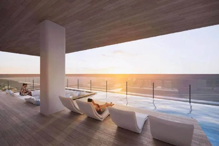 Arom Jomtien rooftop terrace with infinity pool, sun loungers, and ocean sunset view.