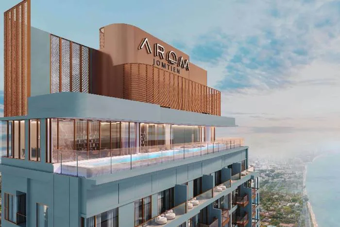 Arom Jomtien high-rise building exterior with rooftop pool and ocean view under a cloudy sky.