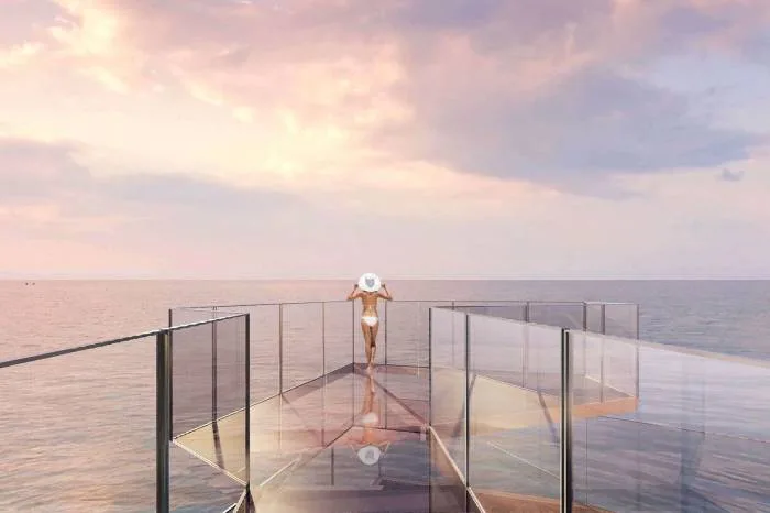 Arom Jomtien glass-bottomed skywalk extending over the ocean with a person in a hat.