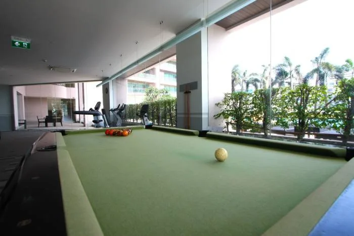 Northshore Pattaya outdoor swimming pool with ocean view, wooden deck, and palm trees under a blue sky.