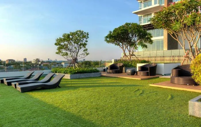 Cetus Beachfront rooftop garden with green artificial grass, outdoor seating, and city views.