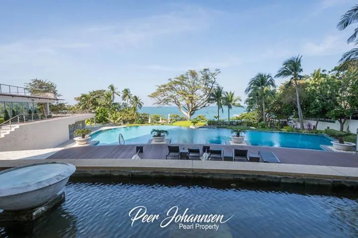 The Cove Pattaya large outdoor swimming pool area with wooden deck, sun loungers, and ocean view.