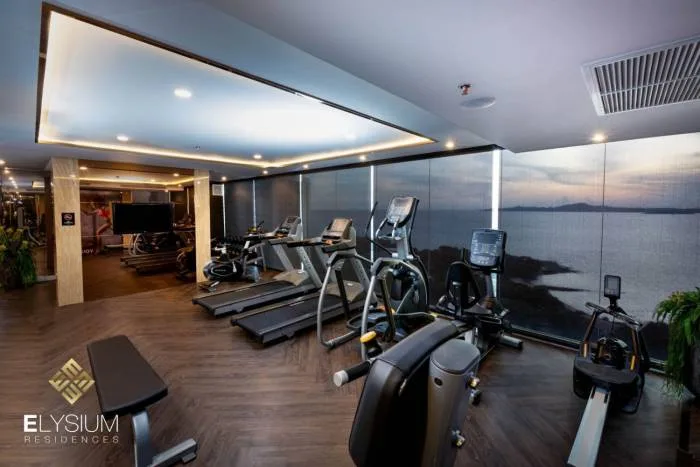 Elysium Residences modern fitness center with treadmills, ellipticals, and a sea view.