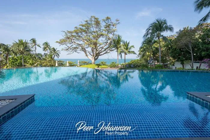 The Cove Pattaya infinity pool with blue mosaic tiles, overlooking the ocean and palm trees.