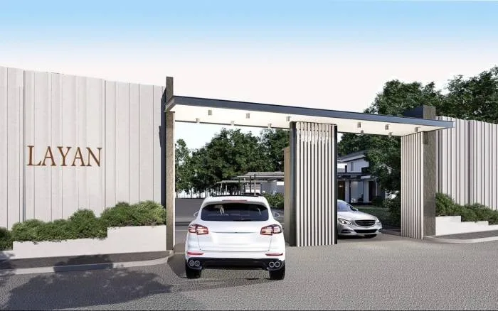 Layan Residence Pattaya modern entrance gate with "LAYAN" sign, white SUV, and green landscaping.