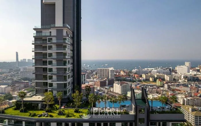 Arcadia Millennium Tower high-rise building with rooftop garden and pool, overlooking Pattaya city and the ocean.