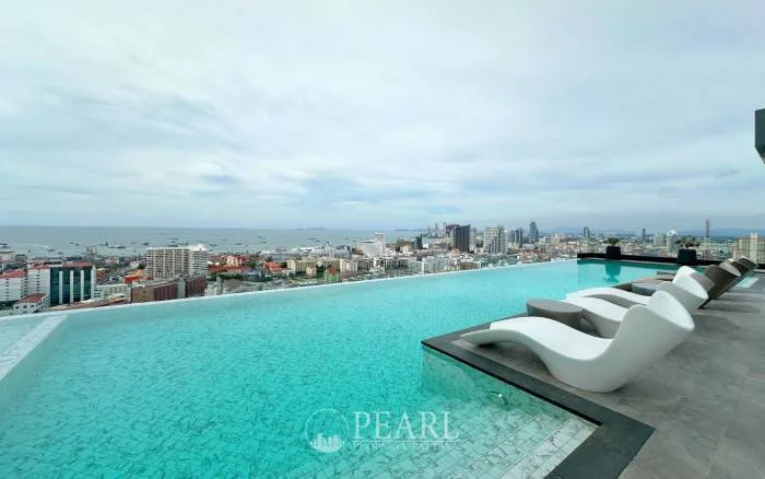 Arcadia Millennium Tower rooftop infinity pool with lounge chairs, offering expansive views of Pattaya city and the ocean.