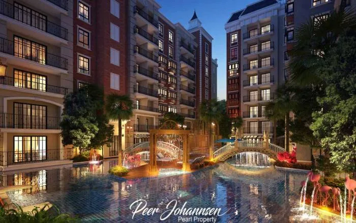 Espana Condo Resort illuminated buildings surrounding a large swimming pool with decorative bridges and fountains at dusk.