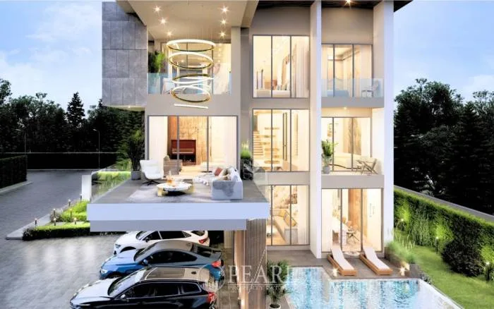 Harmony Hills Villas Pattaya: Modern villa exterior from a different angle, showing the garage and well-lit interiors.