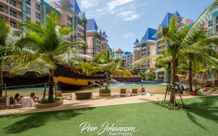 Grande Caribbean resort pool area with a pirate ship, artificial beach, palm trees, and residential buildings.