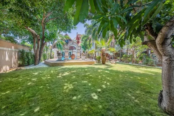Chateau Dale large green lawn with tropical trees, a decorative water feature, and the house in the background.