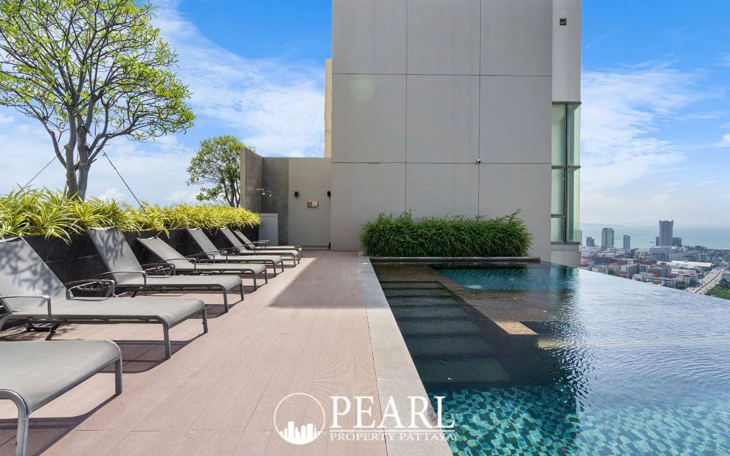 Pattaya Posh tall modern condo building exterior rendering with city and ocean views at sunset.