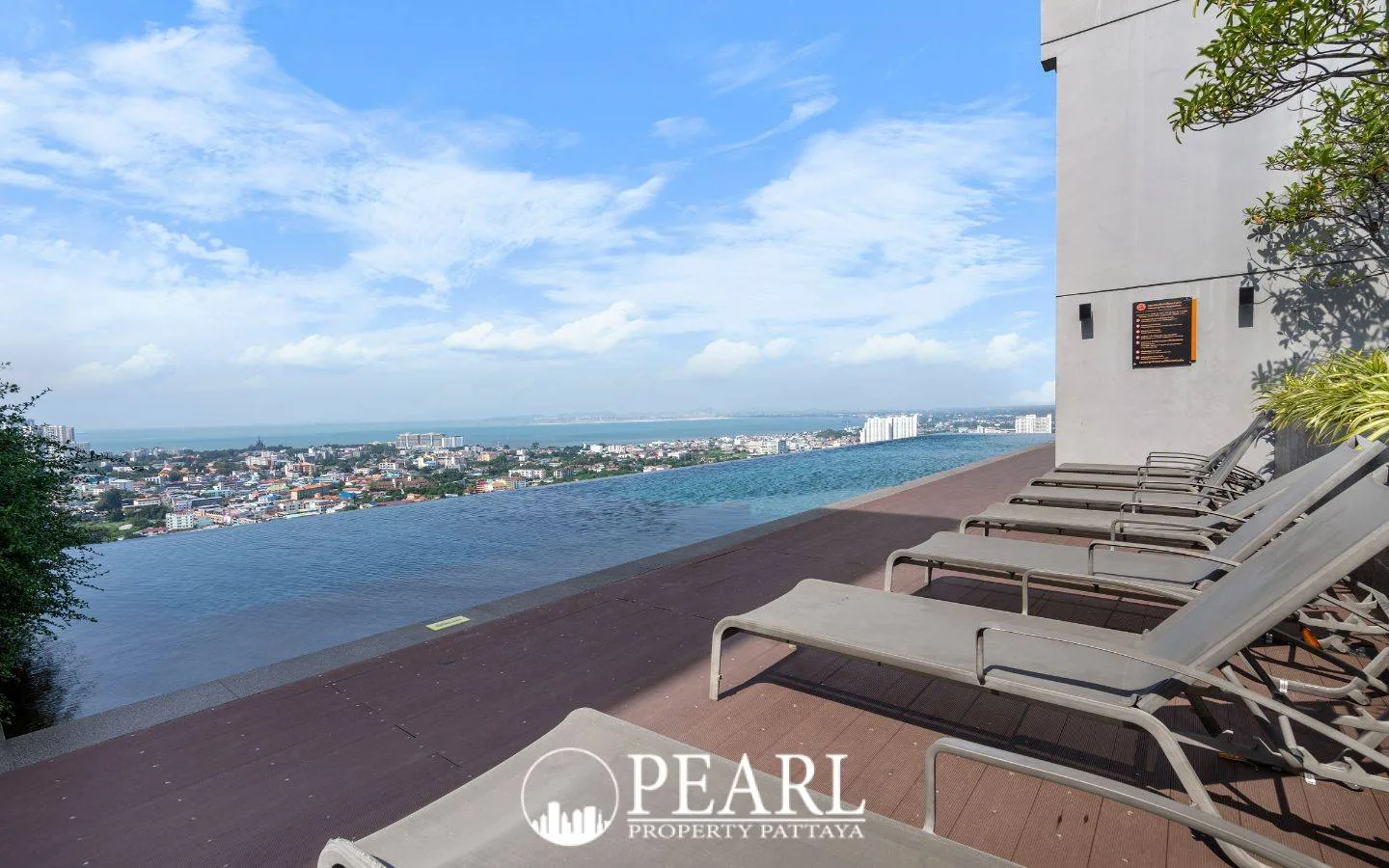 Pattaya Posh rooftop terrace with sun loungers, an infinity pool, and city views.