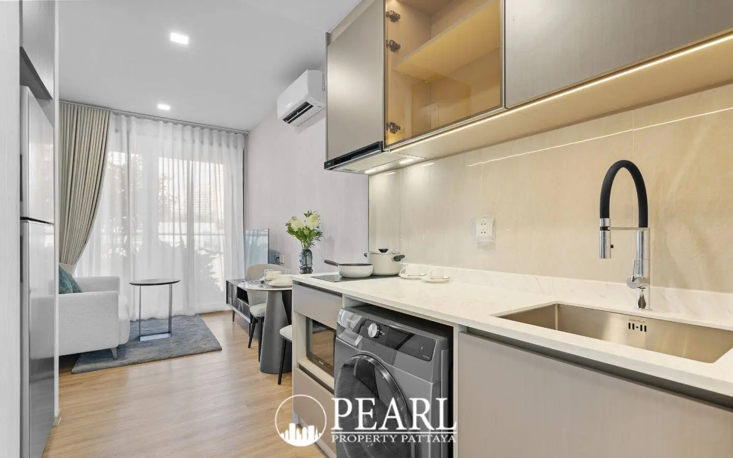 1 Bedroom Condo for Sale at Aquarous Jomtien Pattaya: Kitchenette with built-in appliances, washing machine, and living area view.